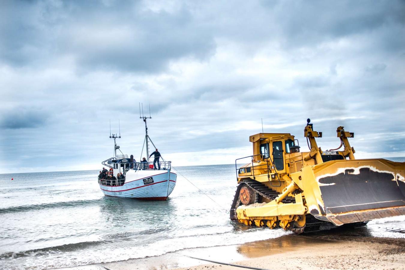 Bulldozer trækker fiskekutter i land